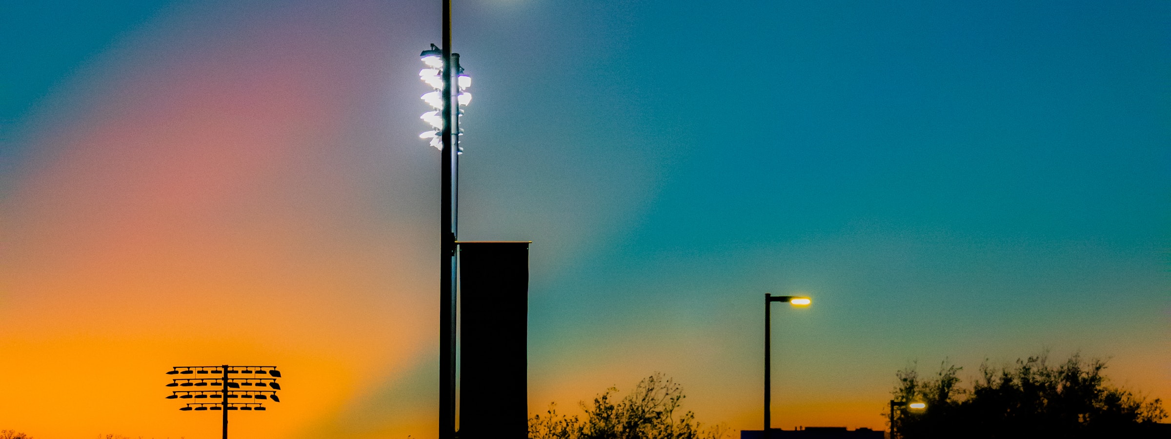 A baseball stadium light tower against a sunset sky